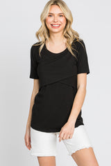 woman wearing a black short sleeve top with a crossover front detail and white denim shorts