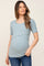woman wearing a light blue ribbed short sleeve maternity top with crossover nursing access and blue jeans