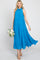 Woman in a sleeveless blue tiered maxi dress holding a bouquet of white roses against a white background