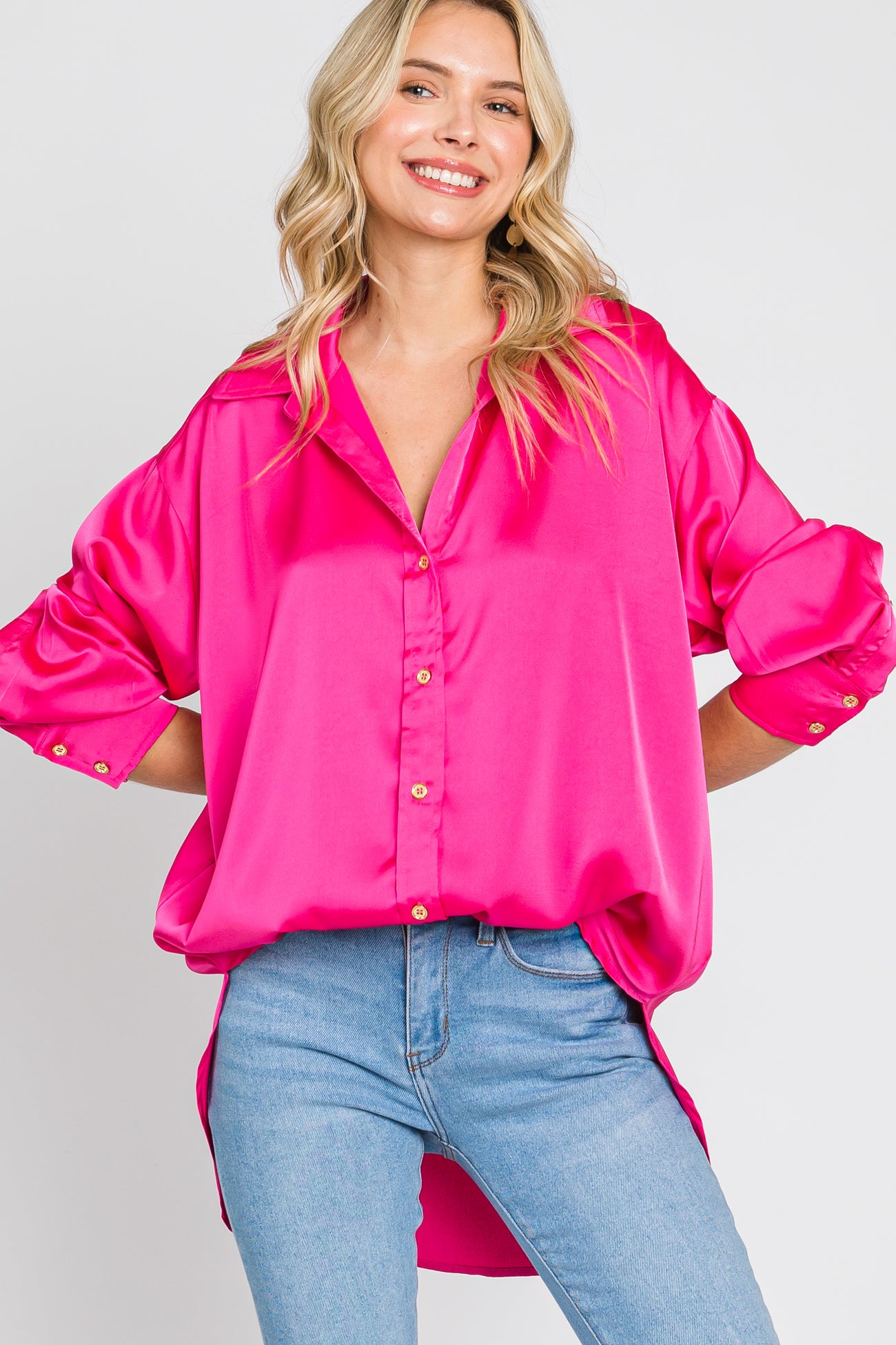 woman wearing a bright pink satin button-down shirt and light wash blue jeans
