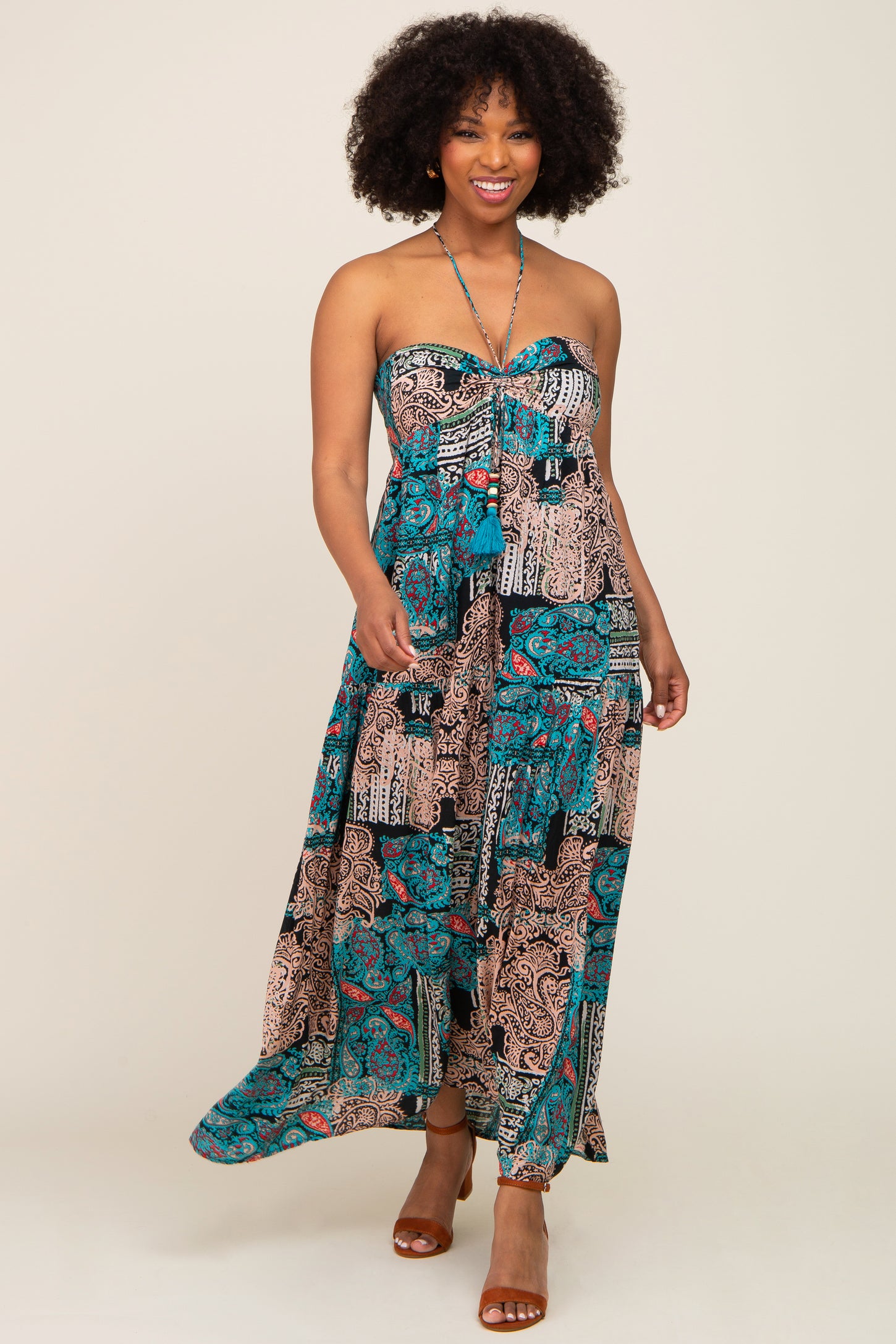 woman wearing a strapless maxi dress with a vibrant paisley pattern in teal and brown tones