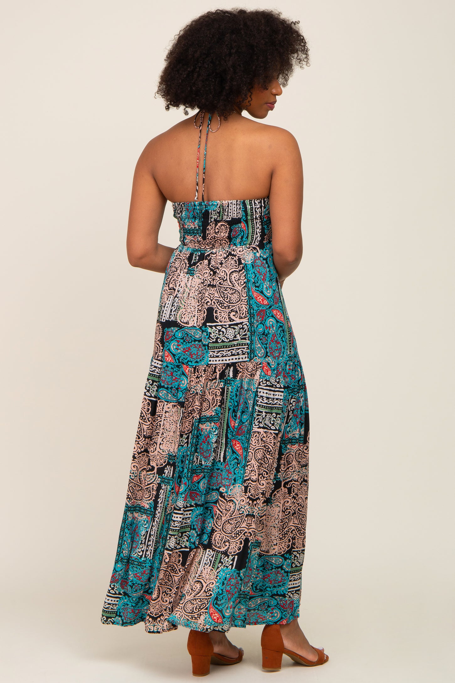 woman wearing a black and teal patterned maxi dress with a halter neck and backless design