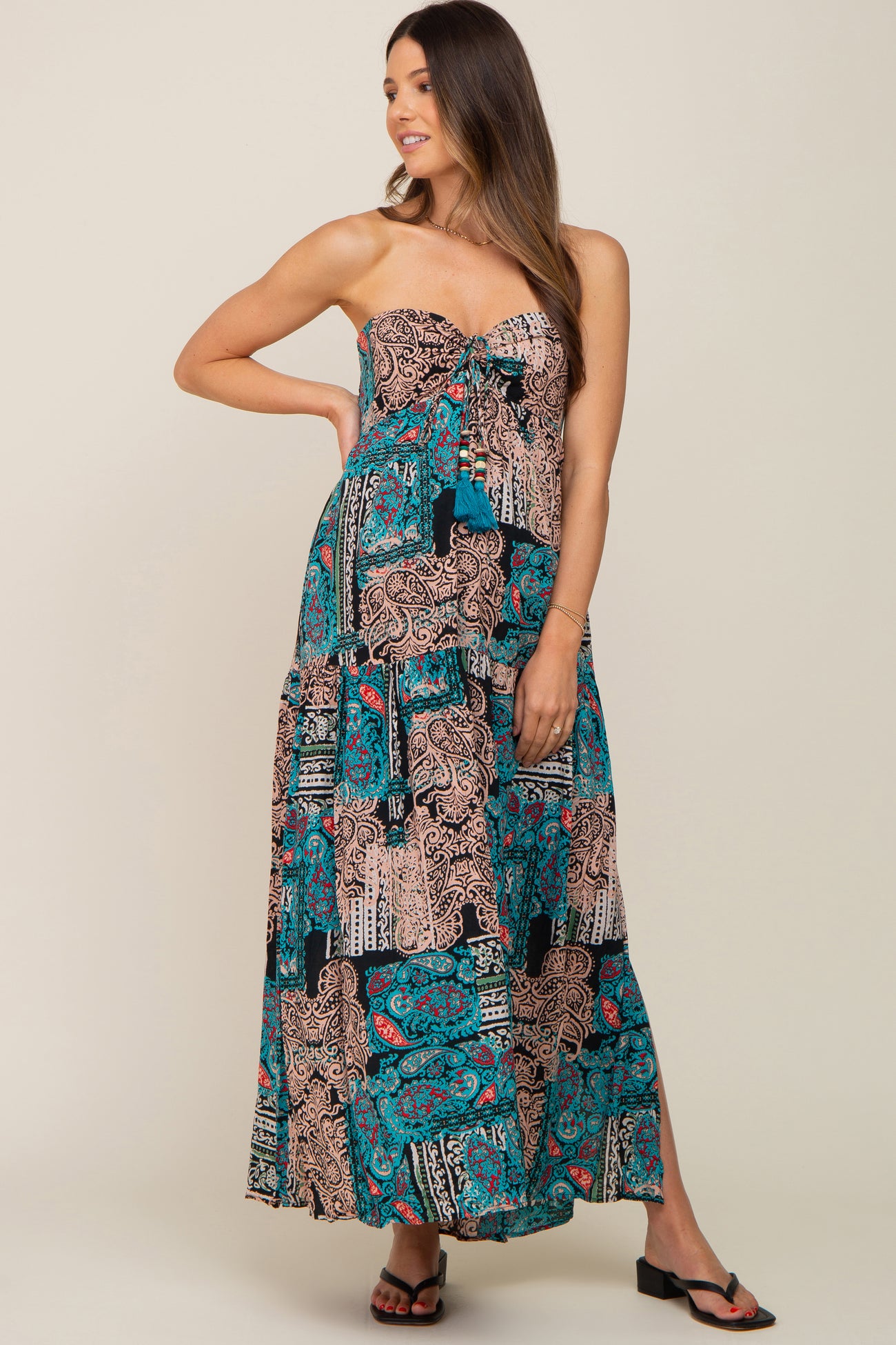 woman wearing a strapless maxi maternity dress with a colorful paisley pattern and a tiered design