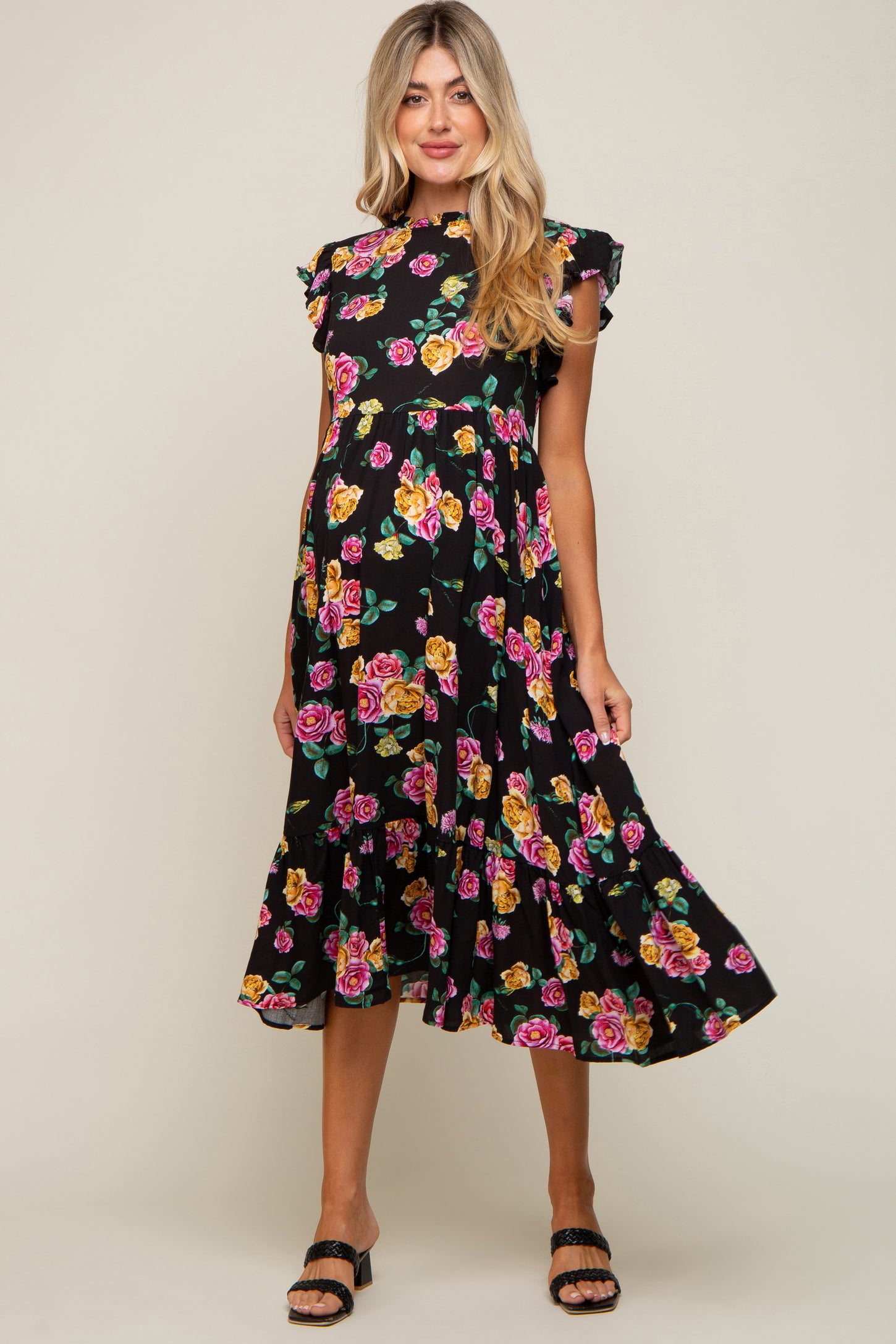 woman wearing a black floral maternity midi dress with pink and yellow roses and ruffle sleeves