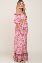 woman wearing a pink floral off-shoulder maternity crop top and matching maxi skirt, showing her baby bump