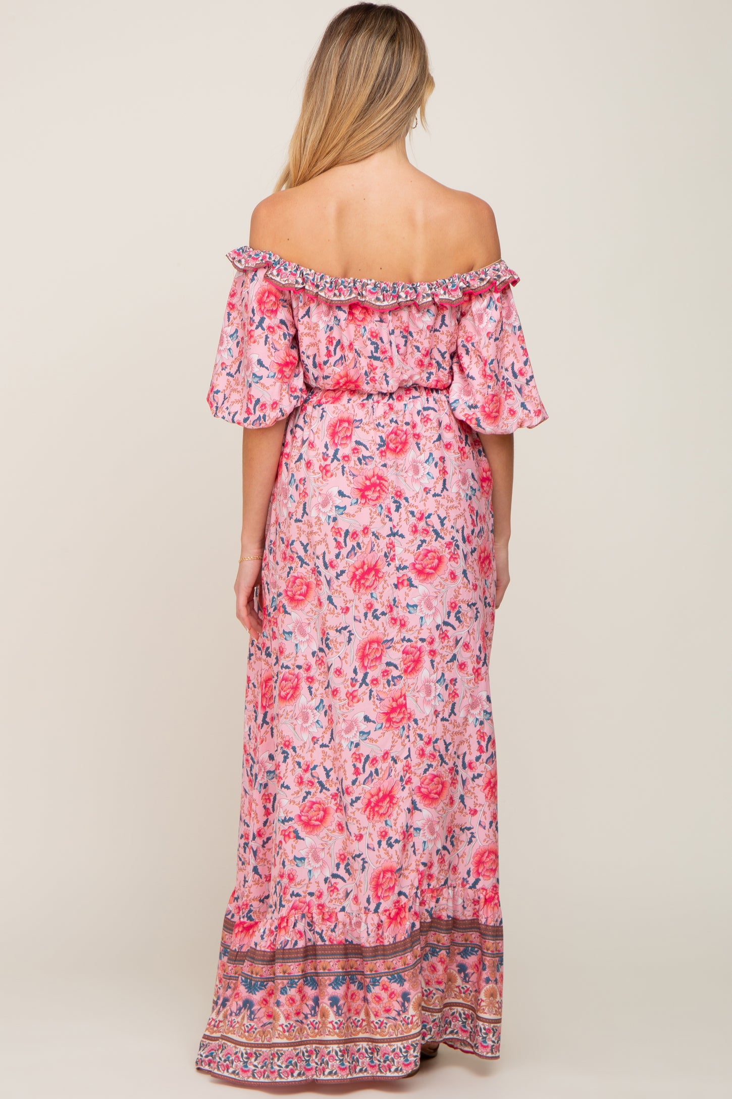 woman wearing a floral off-the-shoulder maternity maxi dress with a flowy silhouette and ruffled sleeves