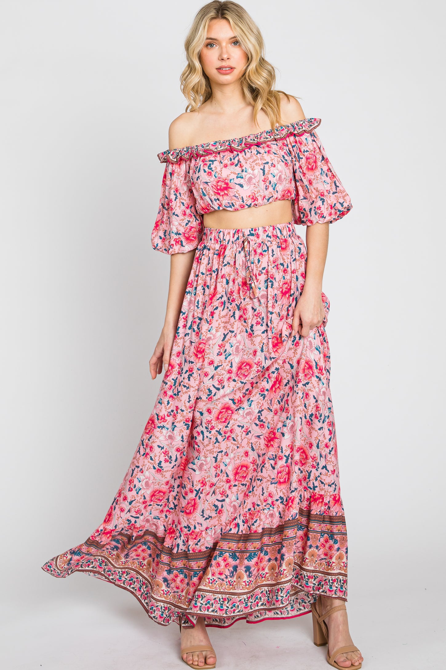 woman wearing a pink floral two-piece maxi dress with off-the-shoulder top and flowing skirt