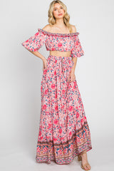 woman wearing a pink floral off-the-shoulder crop top and matching maxi skirt with a wide waistband