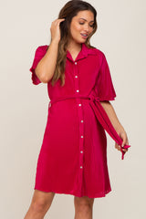 woman wearing a bright pink maternity shirt dress with a belted waist and short sleeves, showing a baby bump