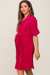 woman wearing a bright pink short sleeve maternity dress with a tie waist and visible baby bump