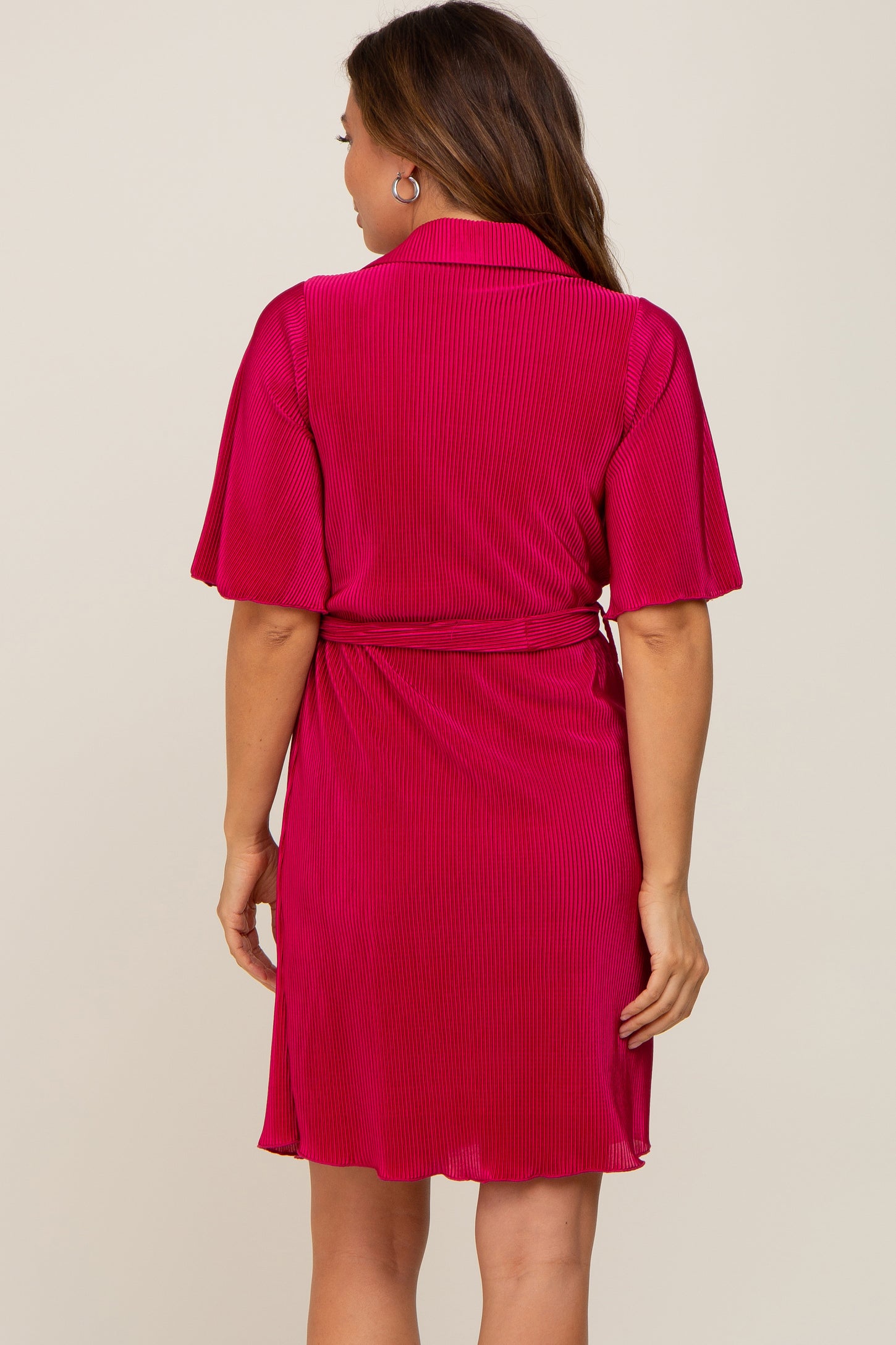woman wearing a bright pink maternity wrap dress with short sleeves and a tie belt, showing a flowing silhouette