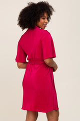 woman wearing a fuchsia short sleeve belted dress with a ribbed texture, showing the back view