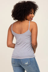 Back view of a woman with curly hair wearing a grey ribbed camisole tank top and blue jeans