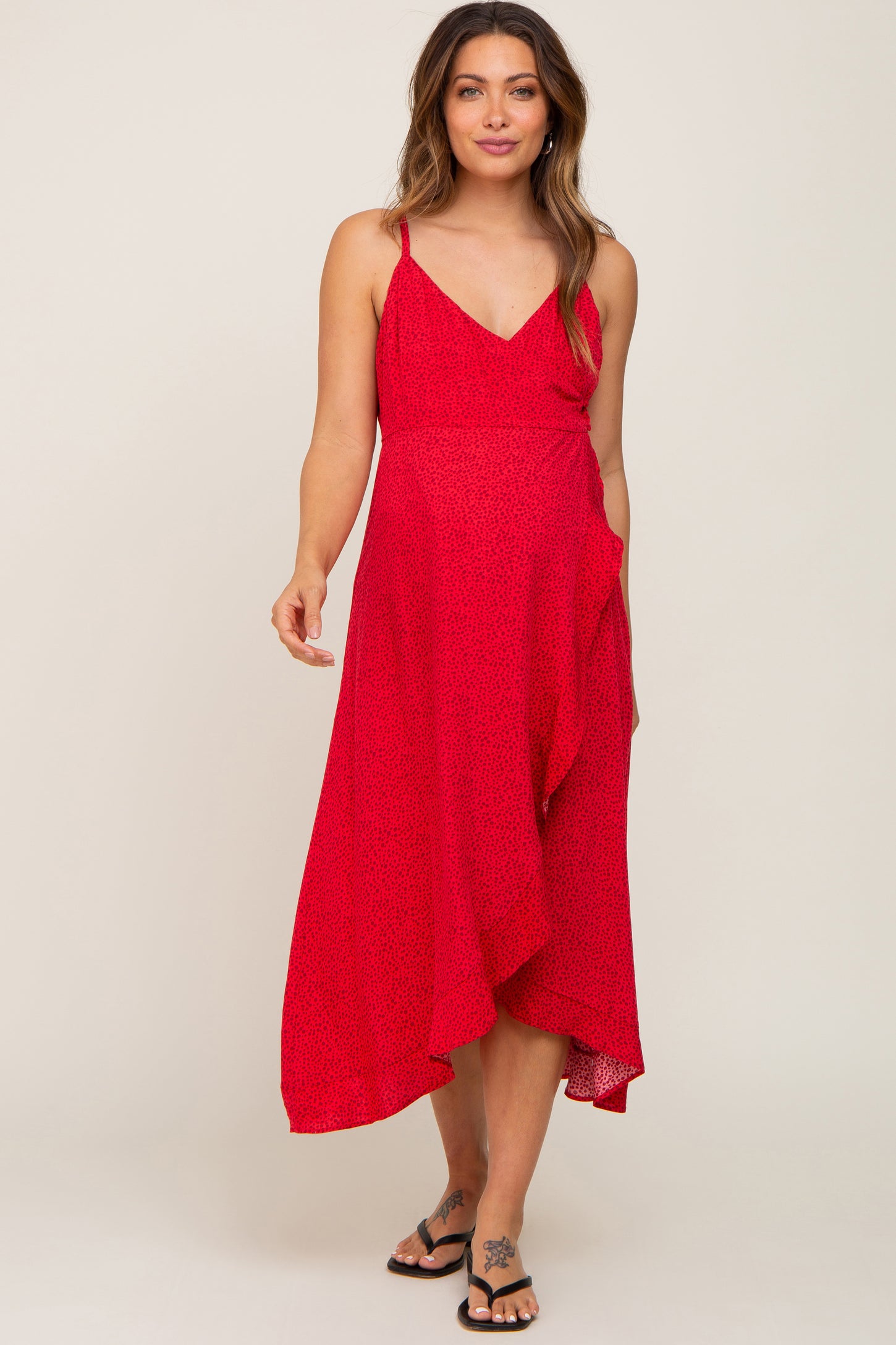woman wearing a red floral print maternity dress with a v-neck and asymmetrical hemline