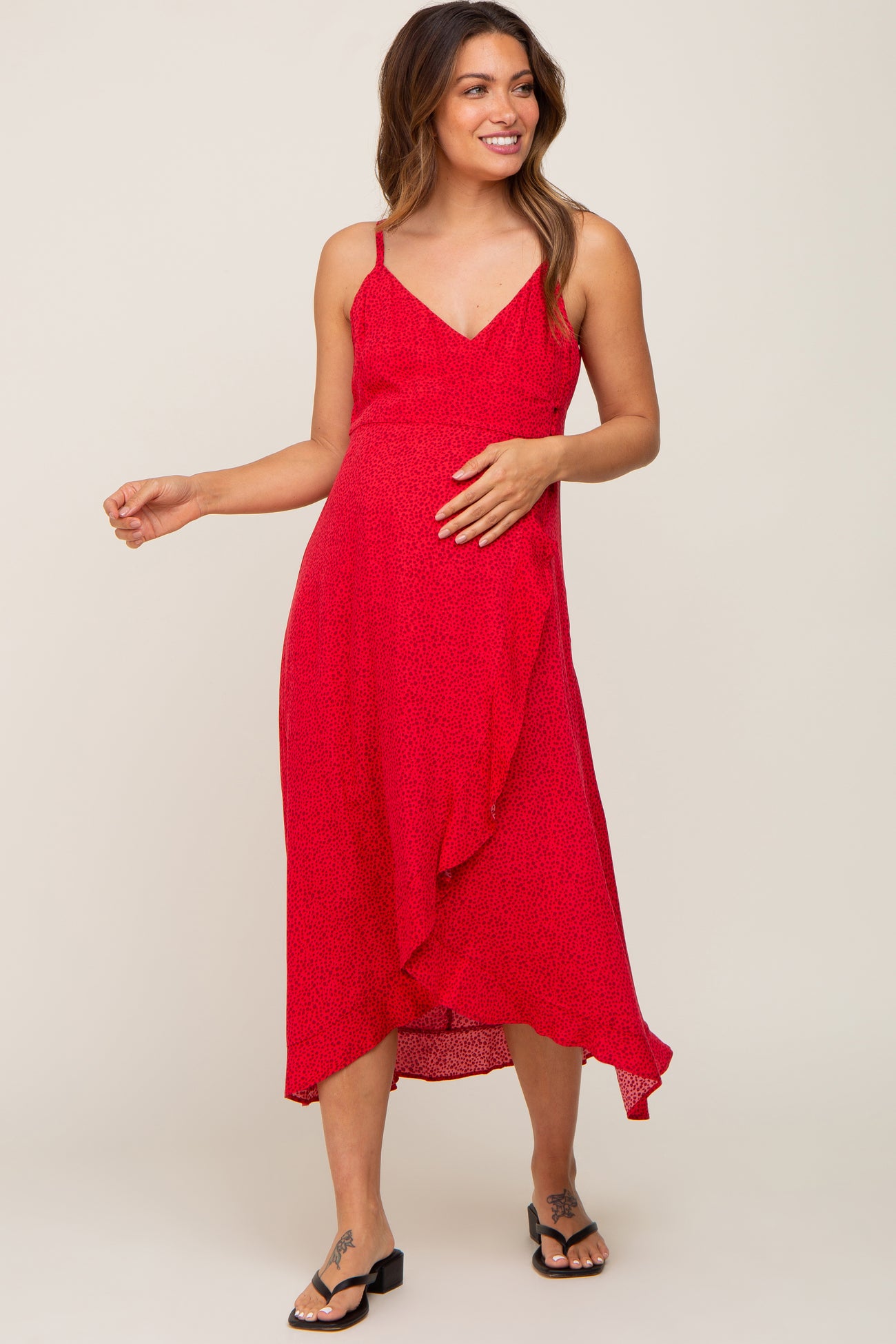 woman wearing a red maternity dress with adjustable straps and asymmetrical hem, showcasing her baby bump