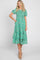 Woman wearing a green floral smocked midi dress with puff sleeves and tiered skirt