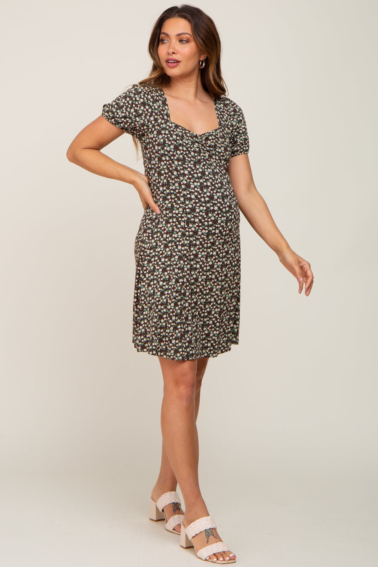 pregnant woman wearing a short sleeve floral maternity dress and white braided heels