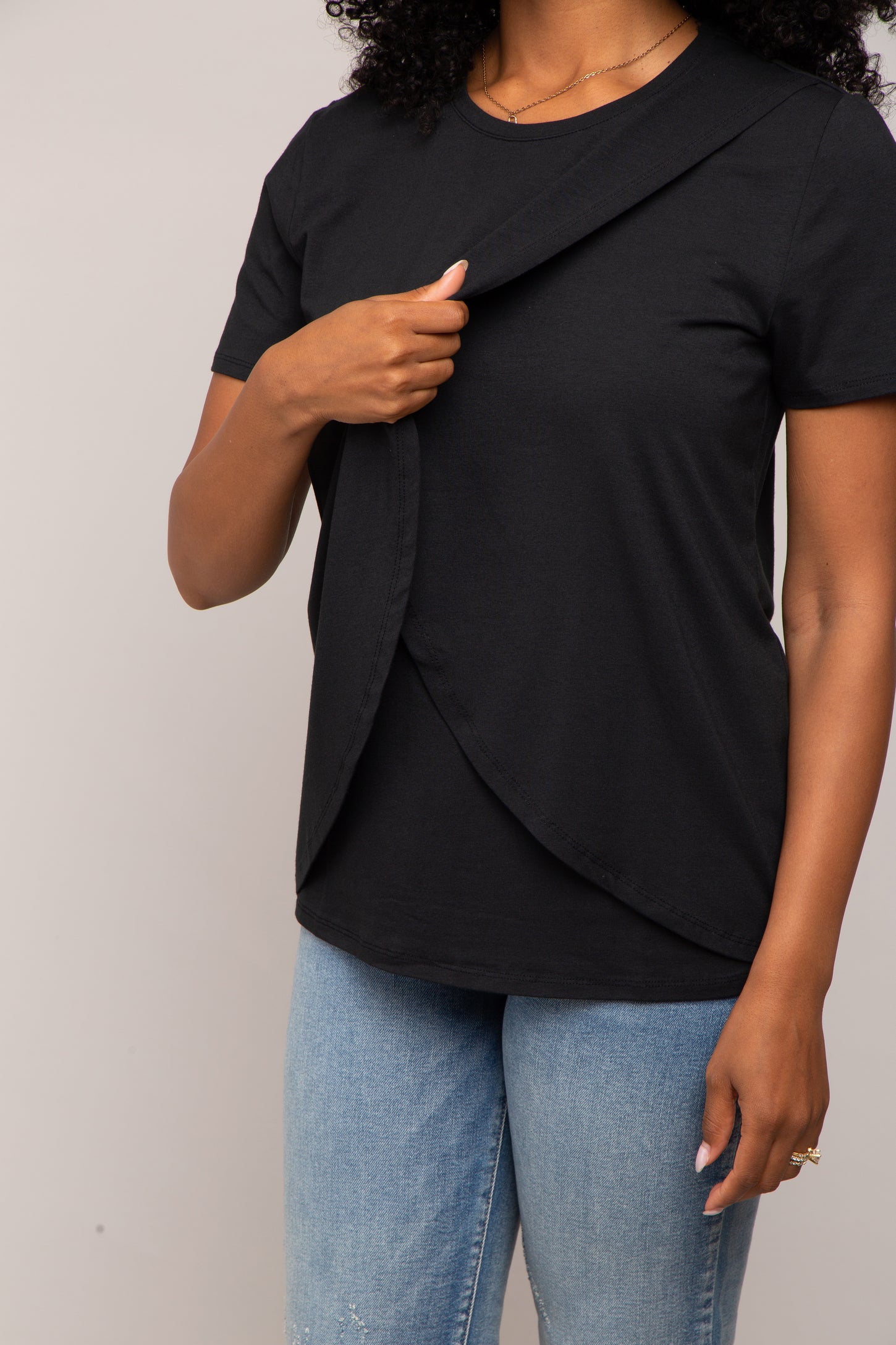 Woman wearing a black short-sleeve nursing t-shirt with a lift-up flap for breastfeeding access.