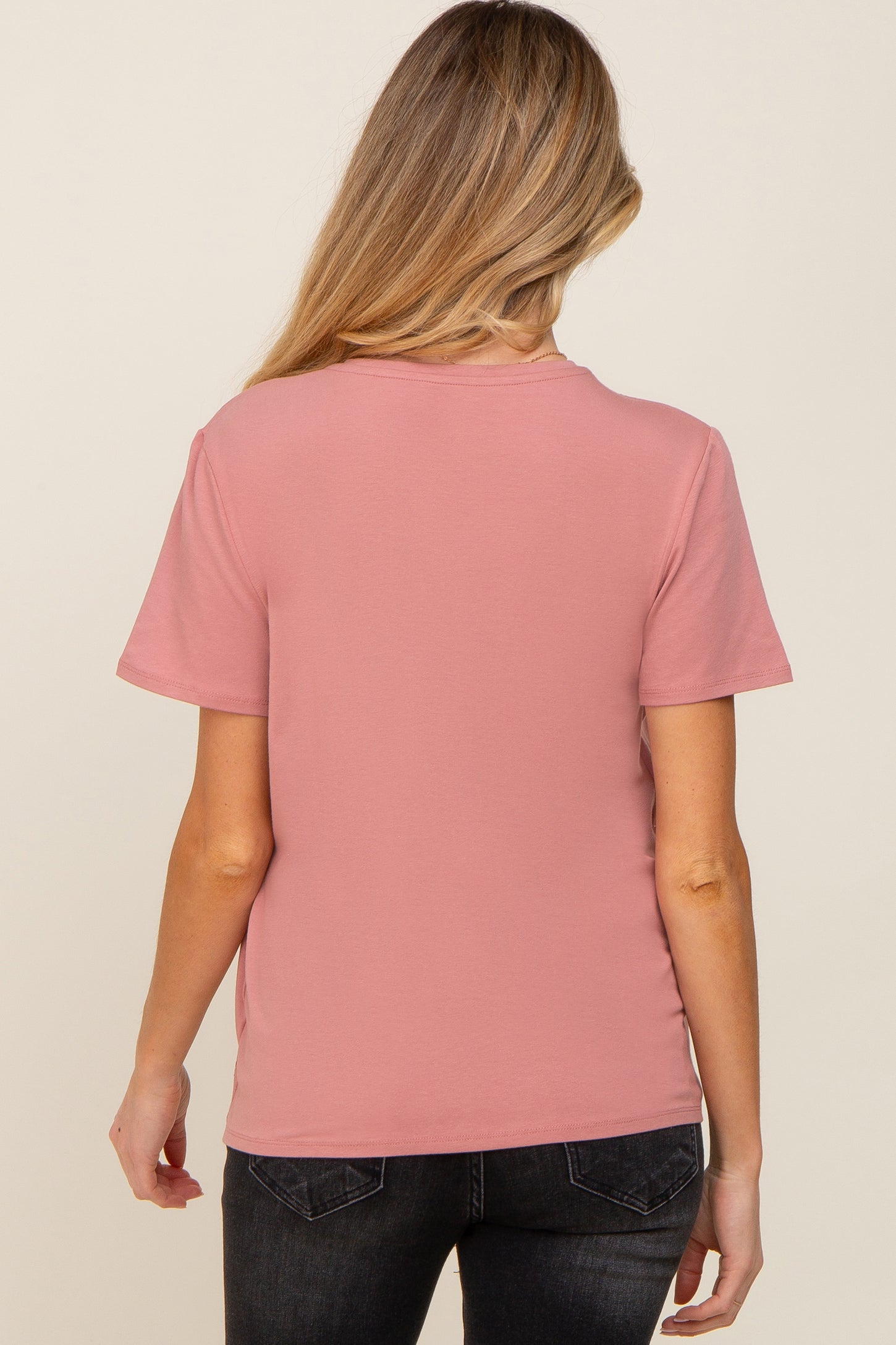 back view of a woman with blonde hair wearing a mauve short sleeve t-shirt and black jeans