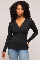 Woman with curly hair wearing a black long-sleeve v-neck wrap top and blue jeans