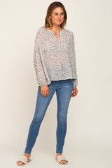 woman wearing a floral print long sleeve blouse and blue skinny jeans with woven slide sandals