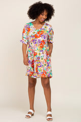 woman with afro hair wearing a colorful floral print babydoll dress and white sandals