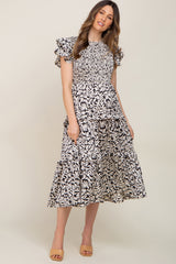 woman wearing a black and white floral print smocked maternity midi dress with ruffle sleeves