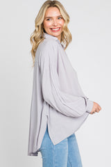 woman wearing a light purple oversized button-down shirt and blue jeans against a white background