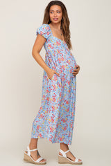 pregnant woman in light blue floral maternity maxi dress with puff sleeves and white wedge sandals