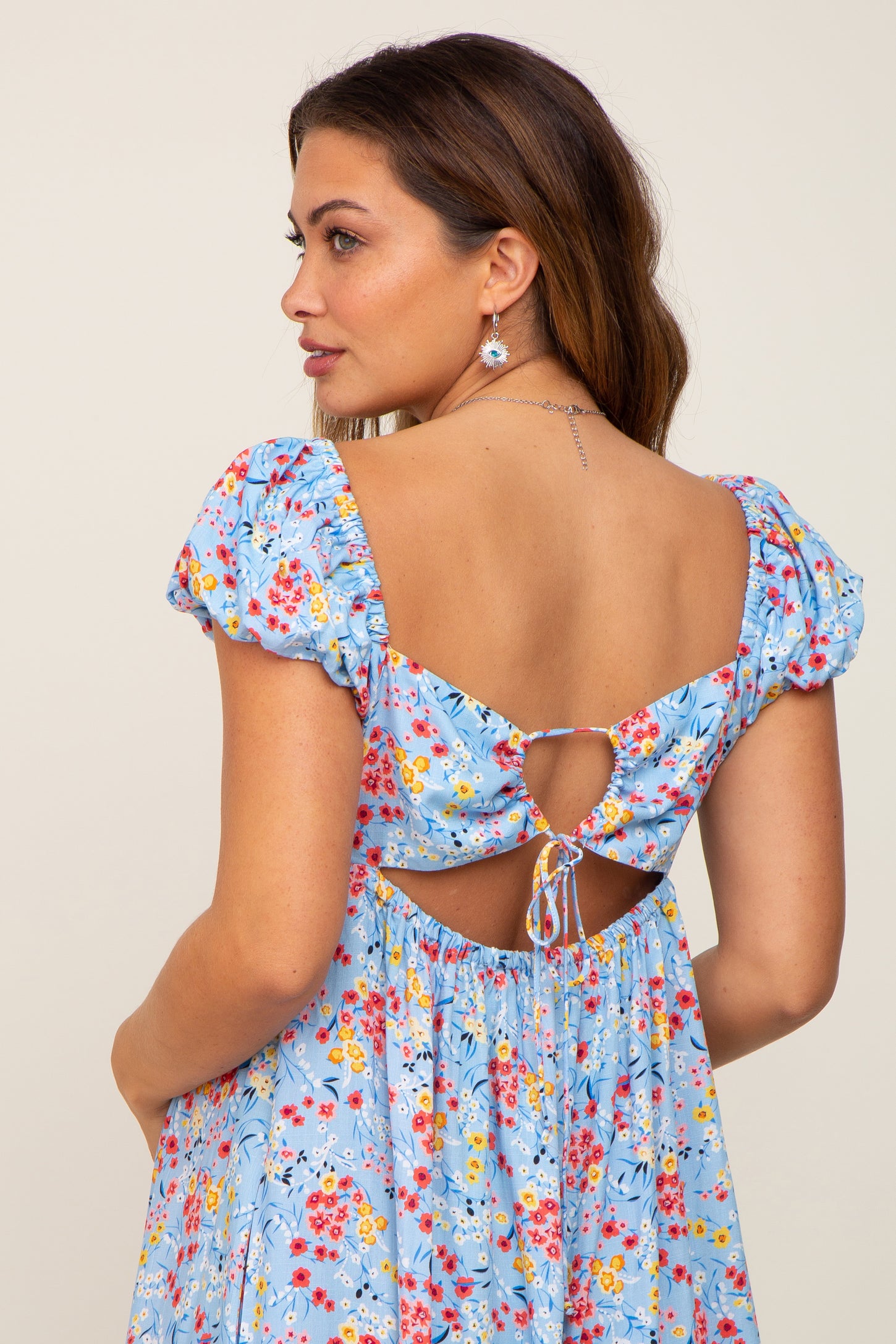 Woman wearing a light blue floral dress with a cutout back and tie detail