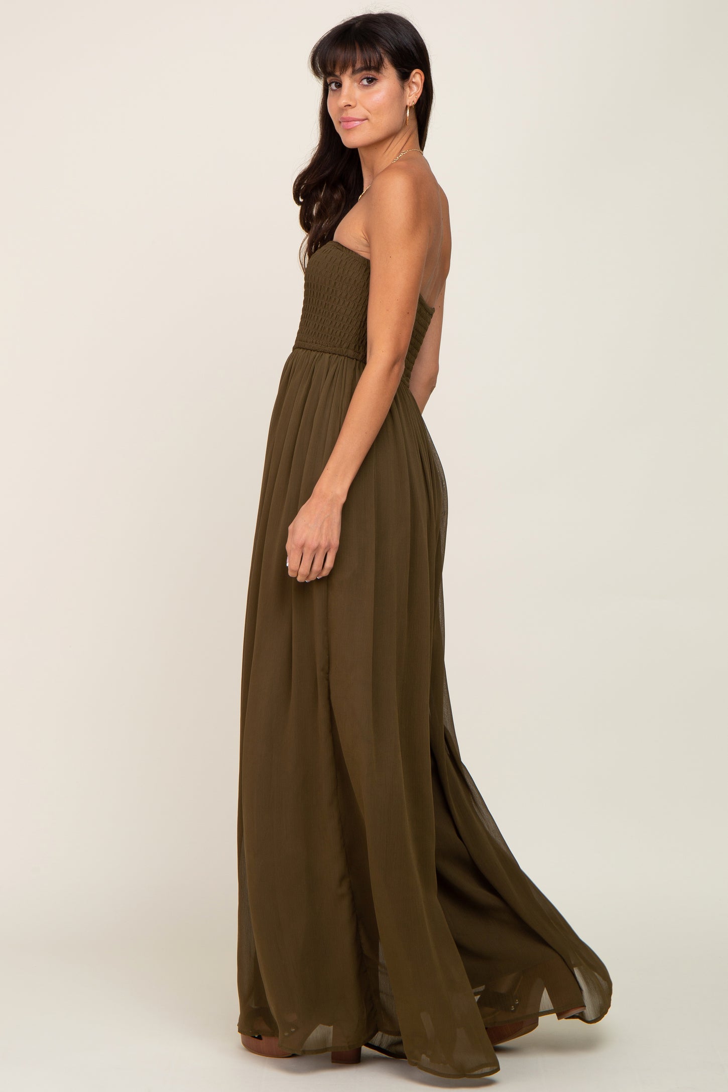 woman wearing an olive green strapless smocked maxi dress against a neutral background