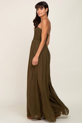 woman wearing an olive green strapless smocked maxi dress against a neutral background