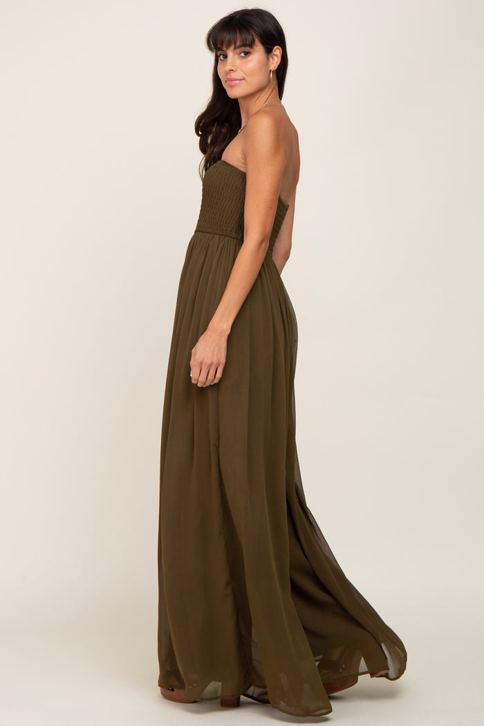 woman wearing an olive green strapless smocked maxi dress against a neutral background