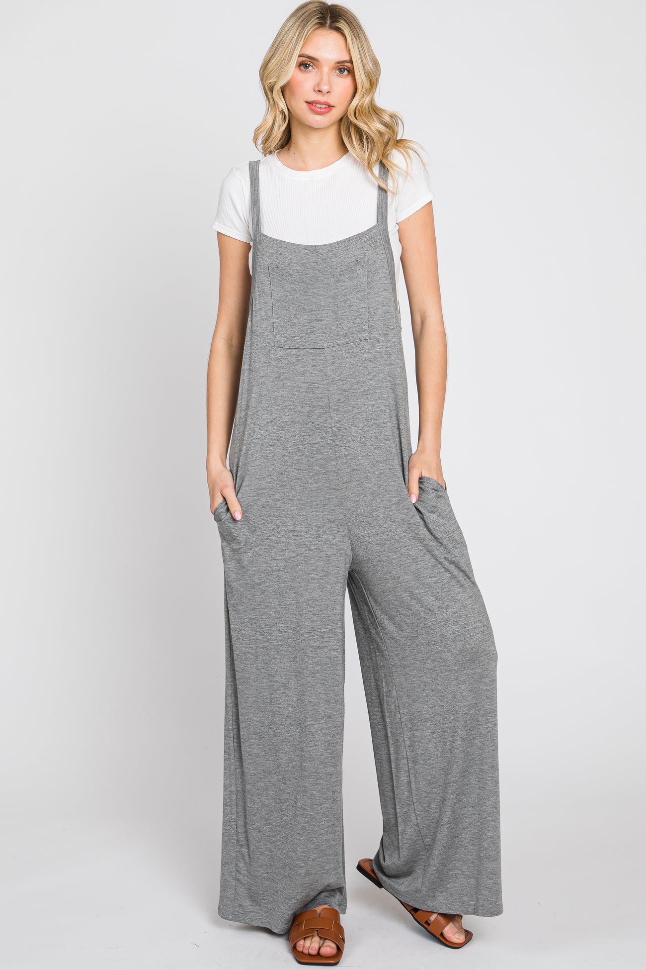 woman wearing a gray wide-leg jumpsuit with pockets over a white t-shirt