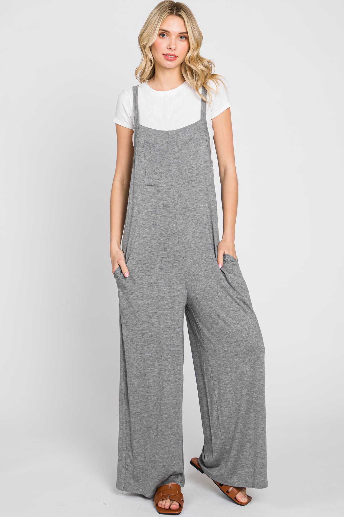 woman wearing a gray wide-leg jumpsuit with pockets over a white t-shirt