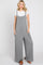 woman wearing a gray wide-leg jumpsuit with pockets over a white t-shirt