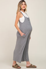 woman wearing a gray maternity jumpsuit with pockets and a baby bump visible