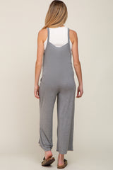 Back view of a woman wearing a grey maternity jumpsuit over a white ribbed tank top