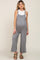 woman wearing a gray maternity jumpsuit with a loose fit and a white tank top, showcasing her baby bump