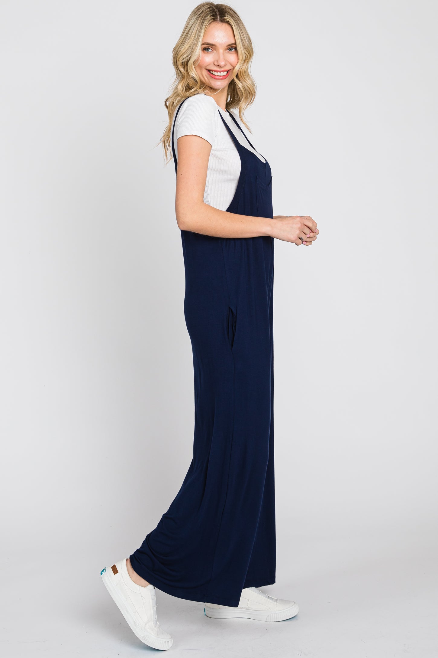 woman wearing a navy blue maxi dress with a fitted white t-shirt underneath and white sneakers