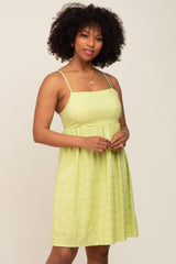 Woman with afro hair wearing a lime green sleeveless babydoll dress and gold necklace