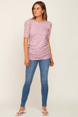 woman wearing a light pink short sleeve top with floral print and ruched sides, paired with blue skinny jeans
