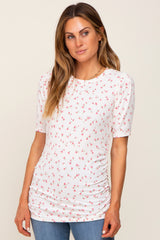 woman wearing a white short sleeve top with pink floral print and ruching details, styled with blue jeans
