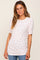 woman wearing a white short sleeve top with pink floral print and ruching details, styled with blue jeans