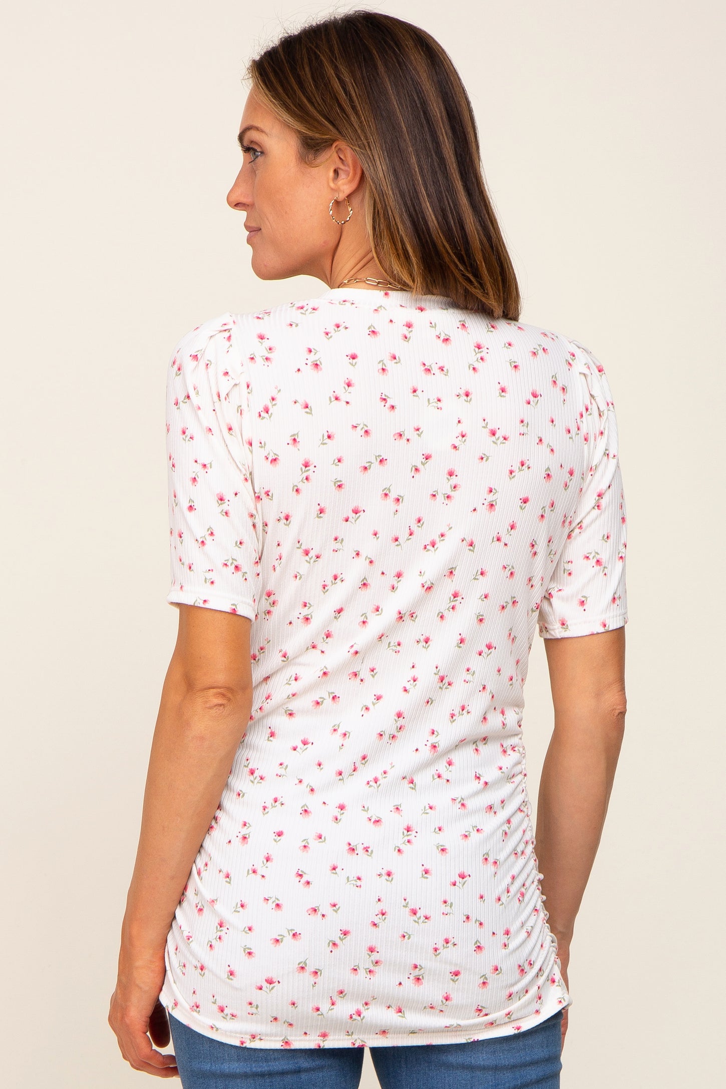woman wearing a white short sleeve top with a floral print and gathered detail at the back