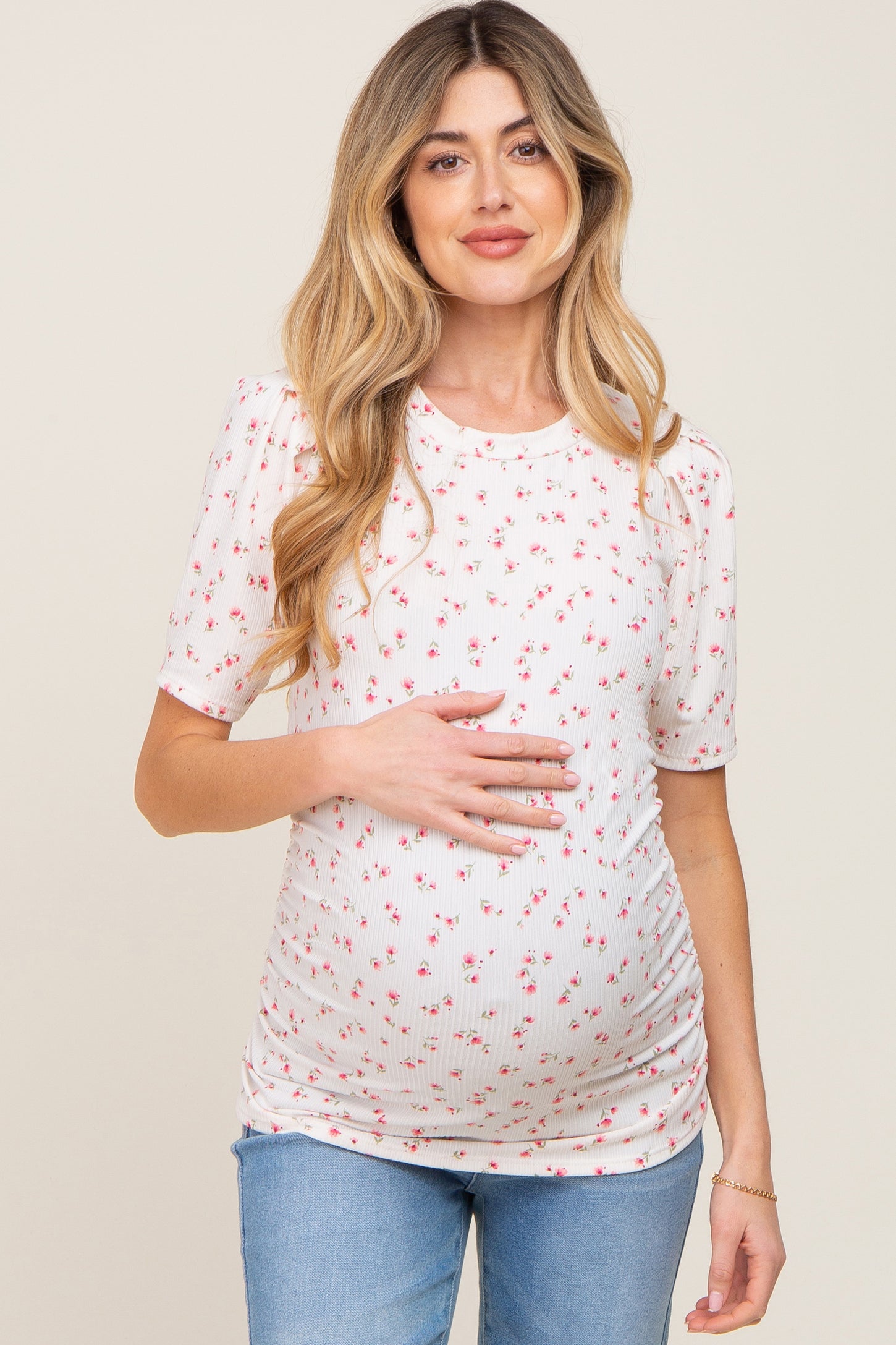 woman wearing a cream floral maternity top with short sleeves and a baby bump visible