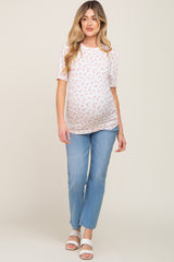 woman wearing a short sleeve floral maternity top and light blue jeans, showing her baby bump
