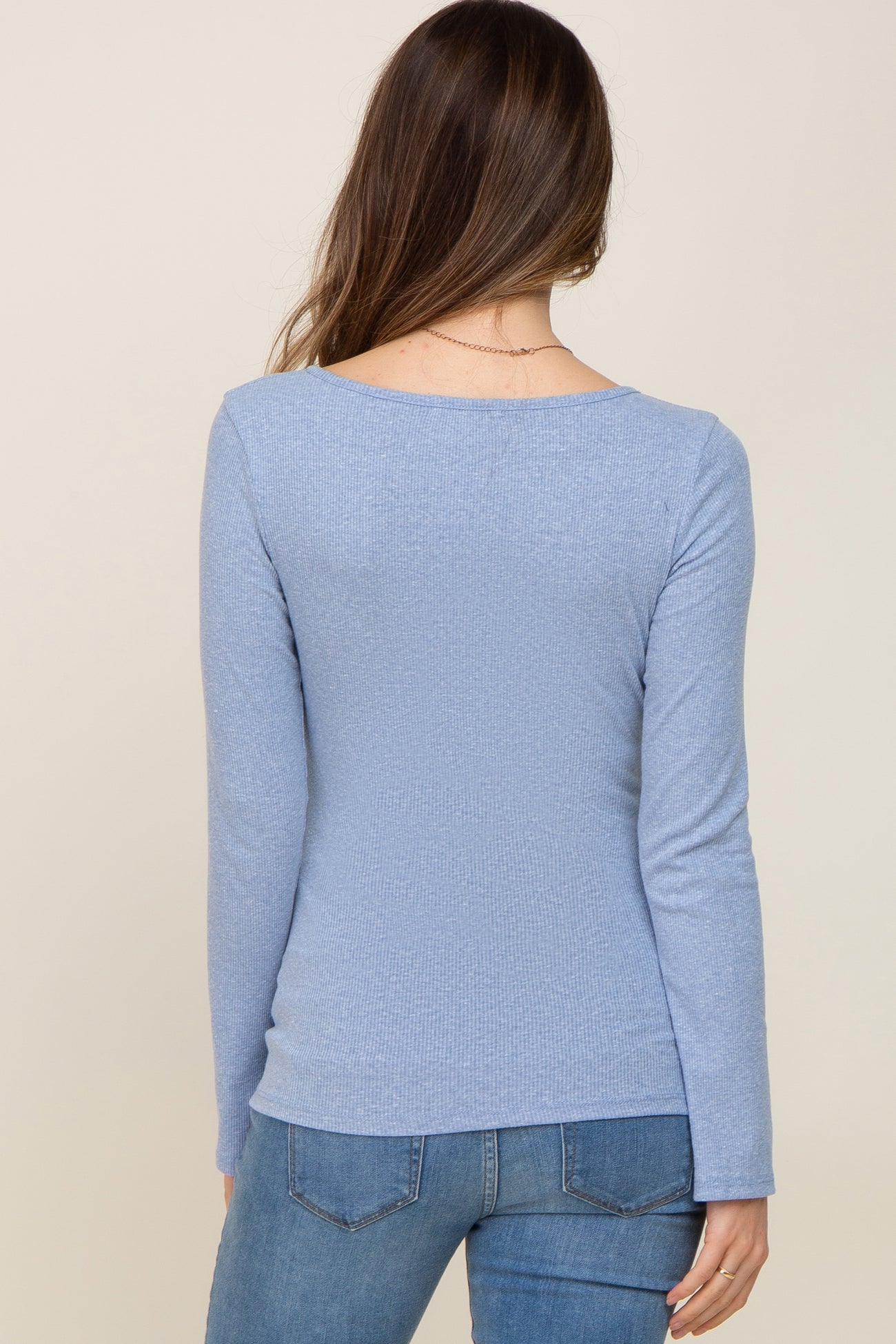 back view of a woman wearing a light blue long sleeve maternity top with a fitted style
