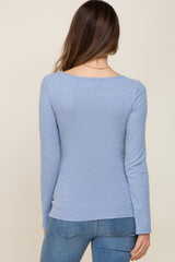 back view of a woman wearing a light blue long sleeve maternity top with a fitted style