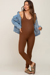 pregnant woman wearing brown ribbed maternity jumpsuit and denim jacket with olive green sandals